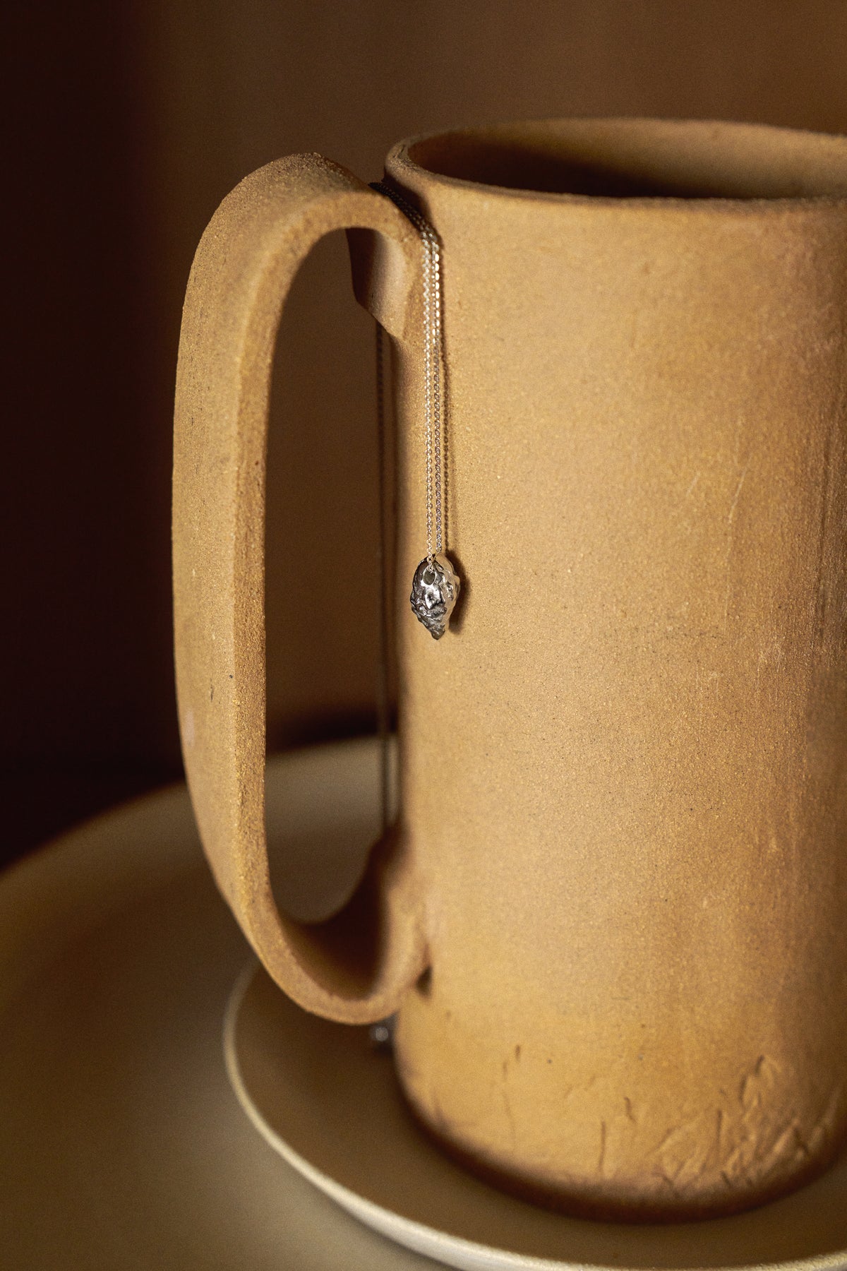 Feggeri shell necklace against a warm-toned ceramic vessel