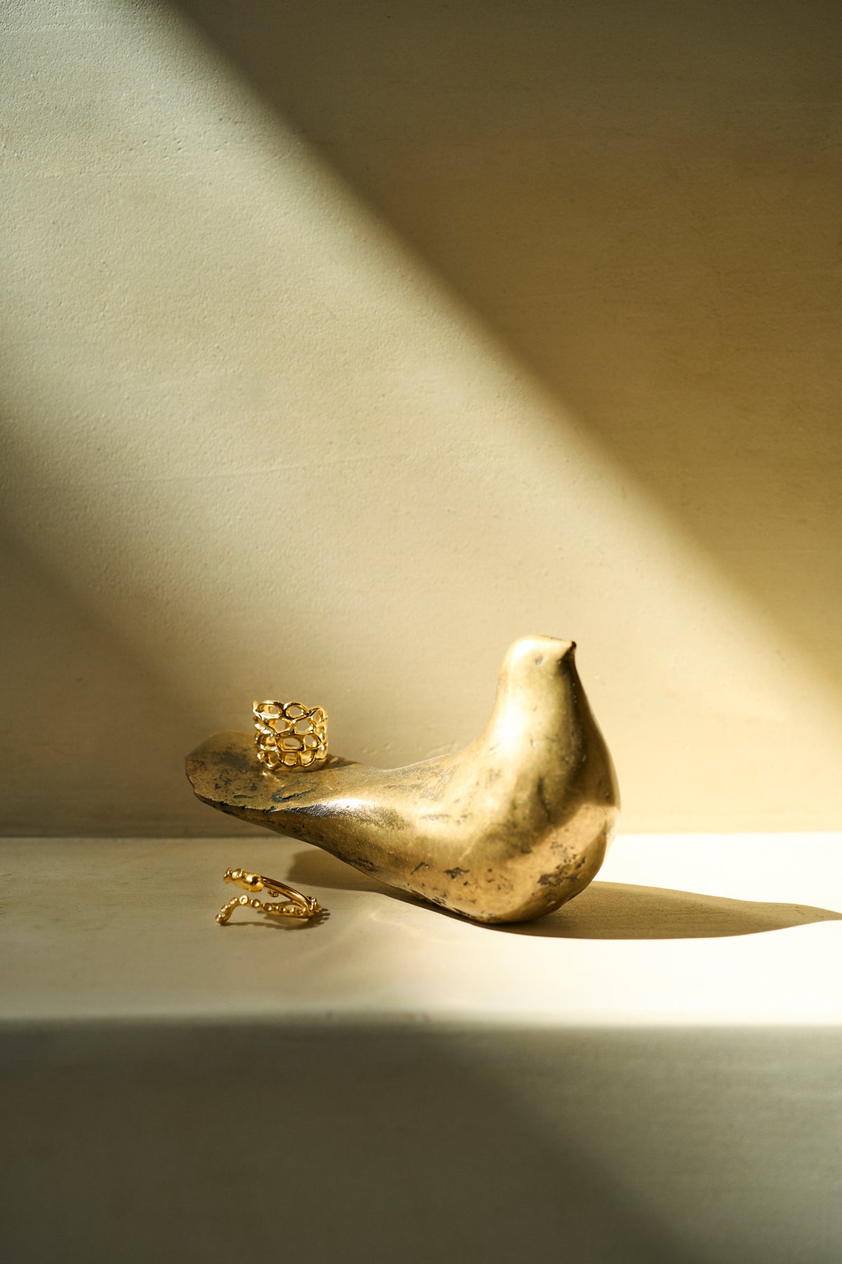 Feggeri gold vermeil rings worn beside a brass bird ornament