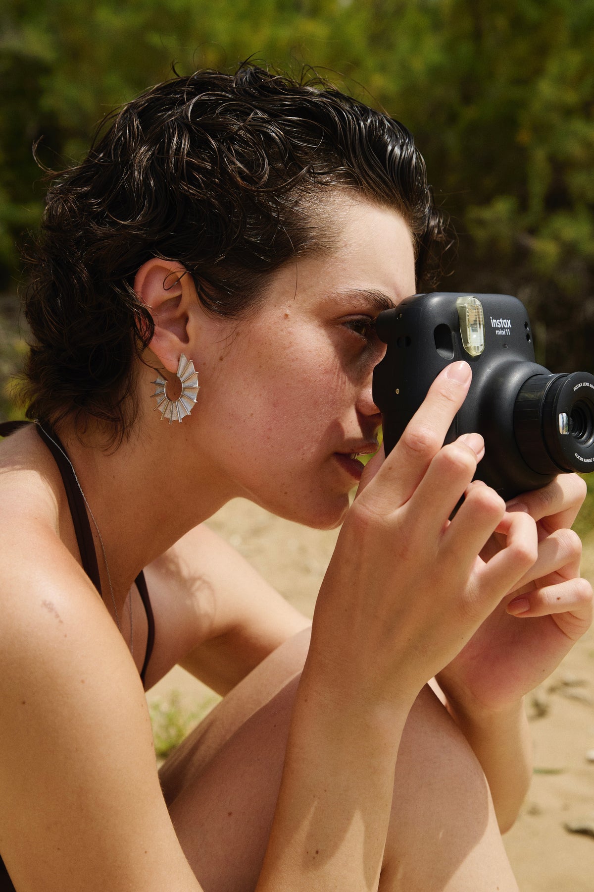Feggeri Ippos fin earrings in sterling silver worn by a model holding a camera