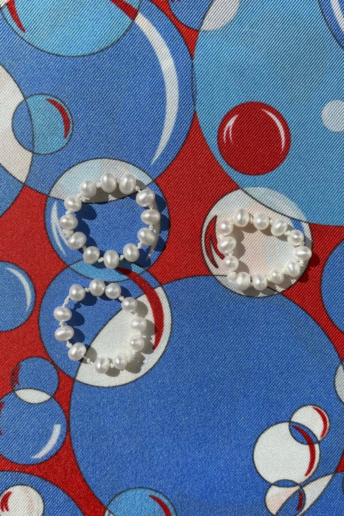 Feggeri knotted freshwater pearl rings on a colourful patterned surface