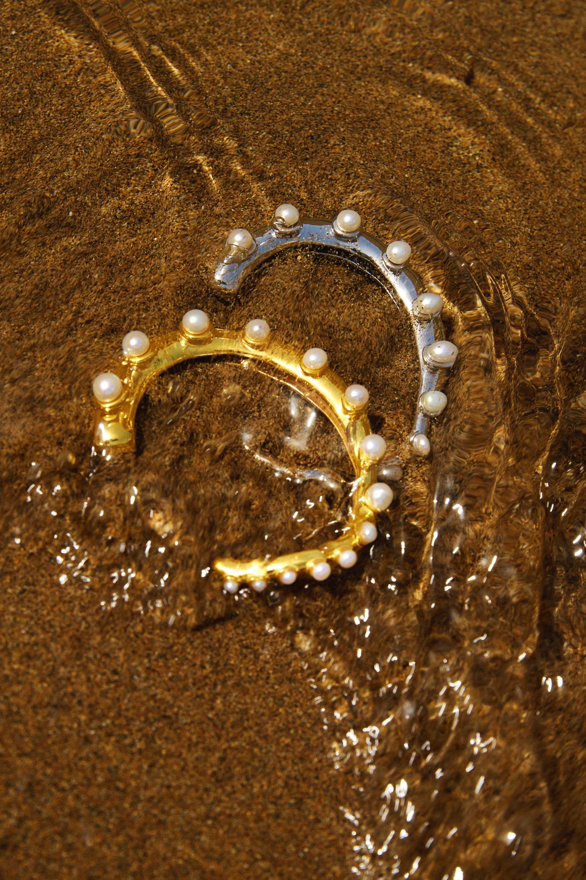 Feggeri Okto freshwater pearl cuffs in gold vermeil and sterling silver together in shallow water