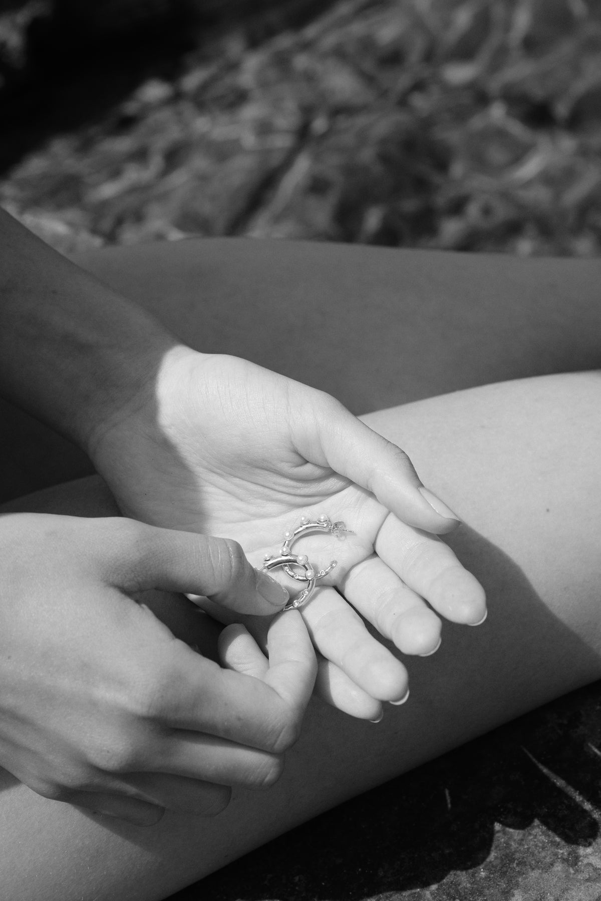 Feggeri Okto pearl hoop earrings held in the hands, photographed in black and white